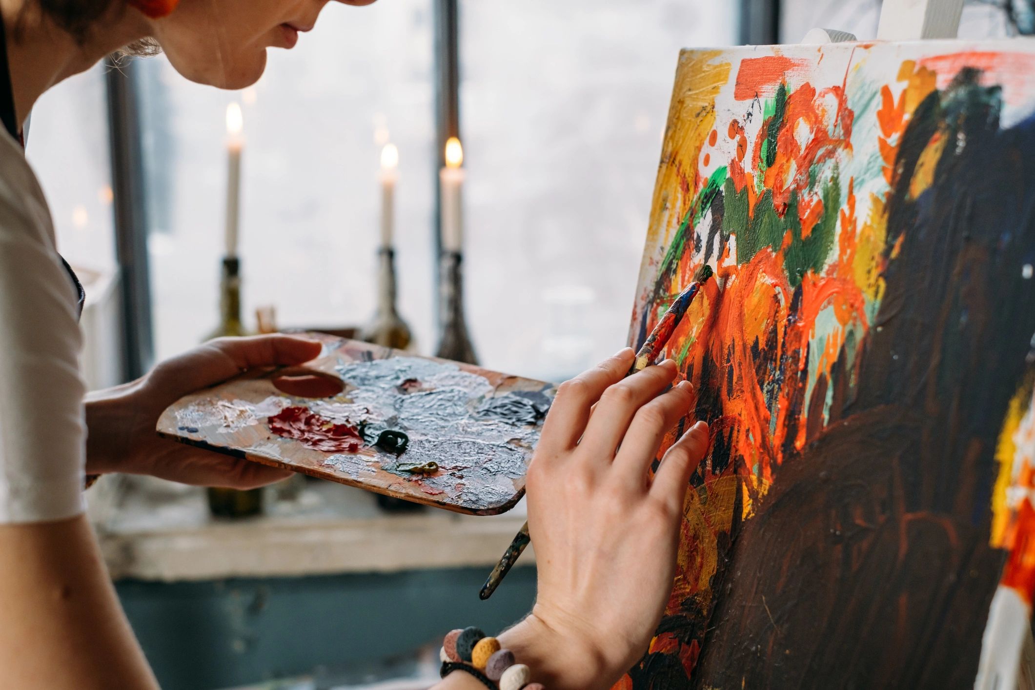 Artist painting on canvas in a light-filled studio