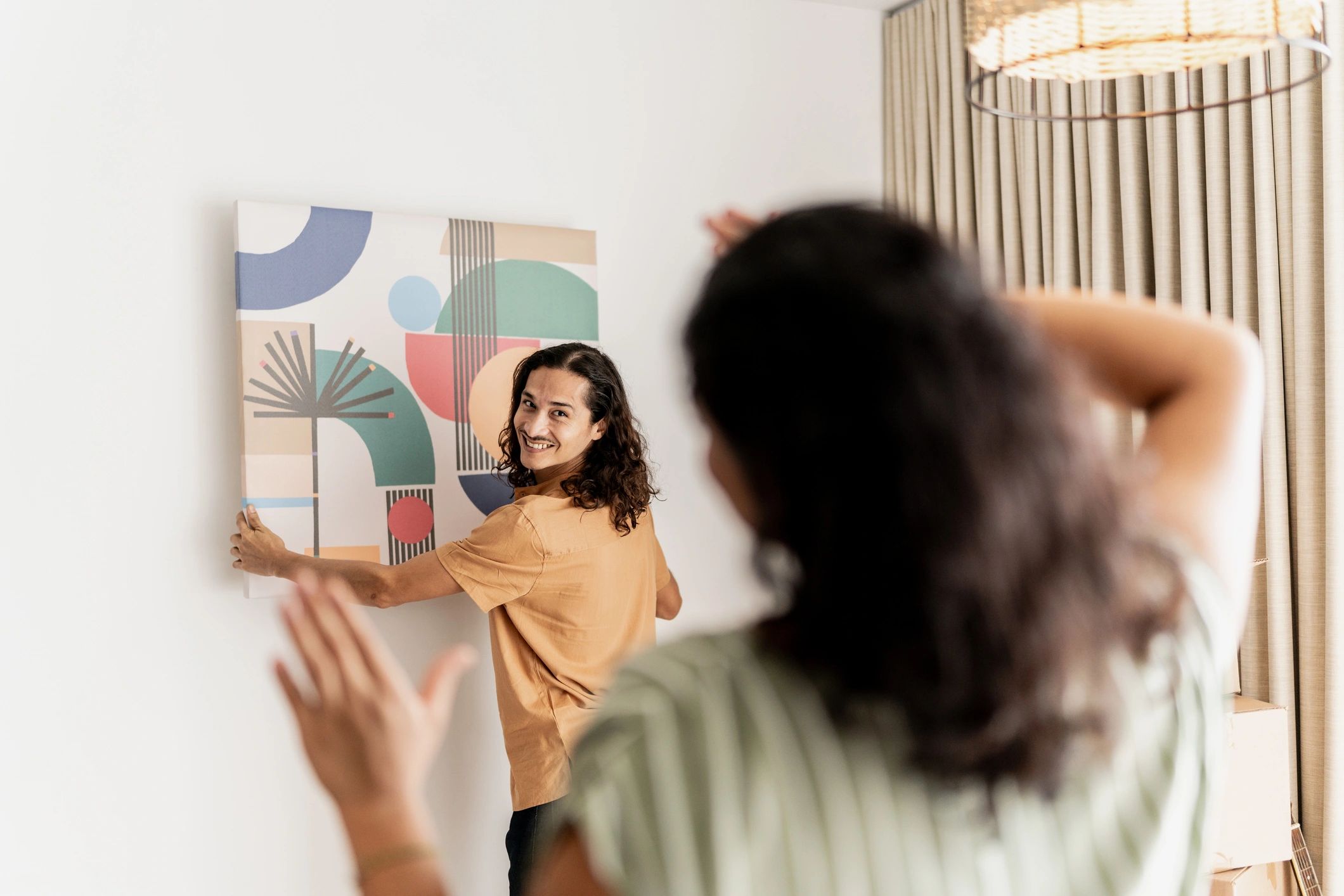 Couple holding a frame and planning wall art placement in a living room