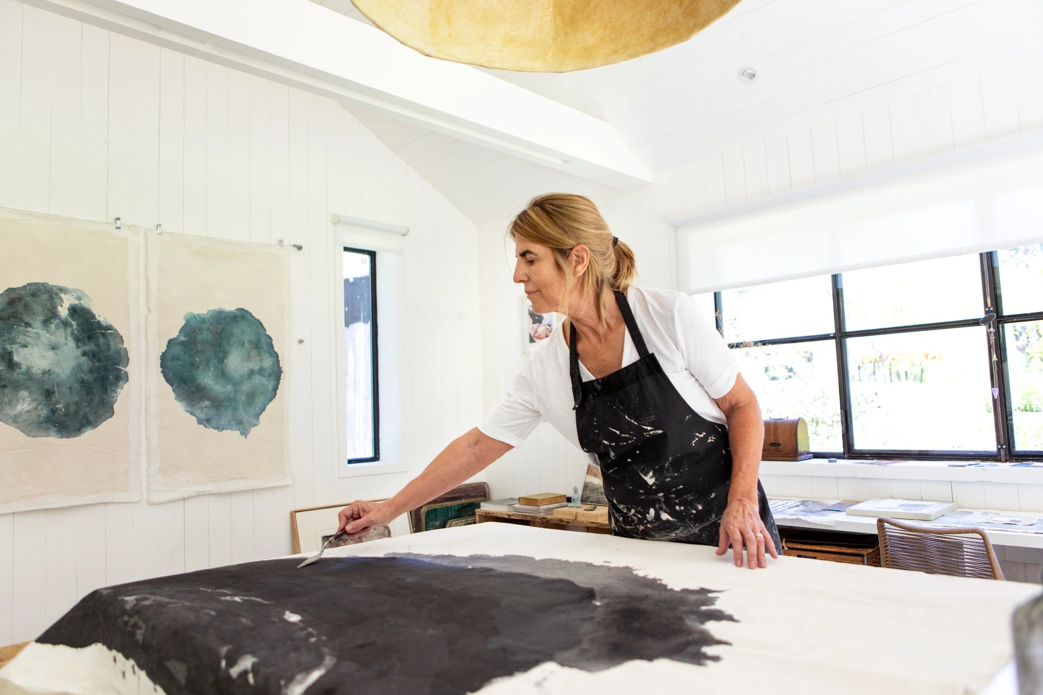 Artist working in studio with paint poured onto canvas